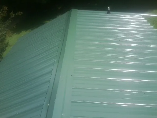New green metal panels meeting at the ridge of a roof — Flat Roof Repair work by our crew in Chillicothe