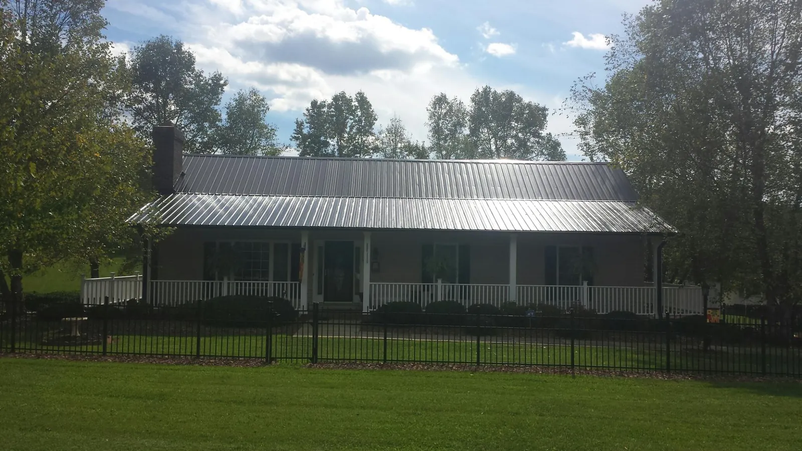 Gray metal roof on a brick ranch with a full width front porch — Gutter Guard Installation work by our crew in Chillicothe