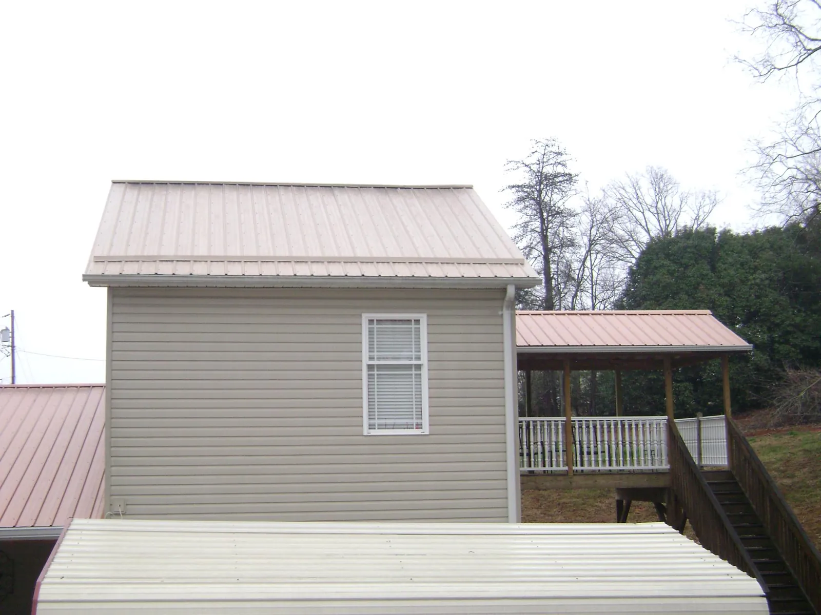Tan metal roofs on a two story addition and attached porch, from a Roof Replacement job in Chillicothe