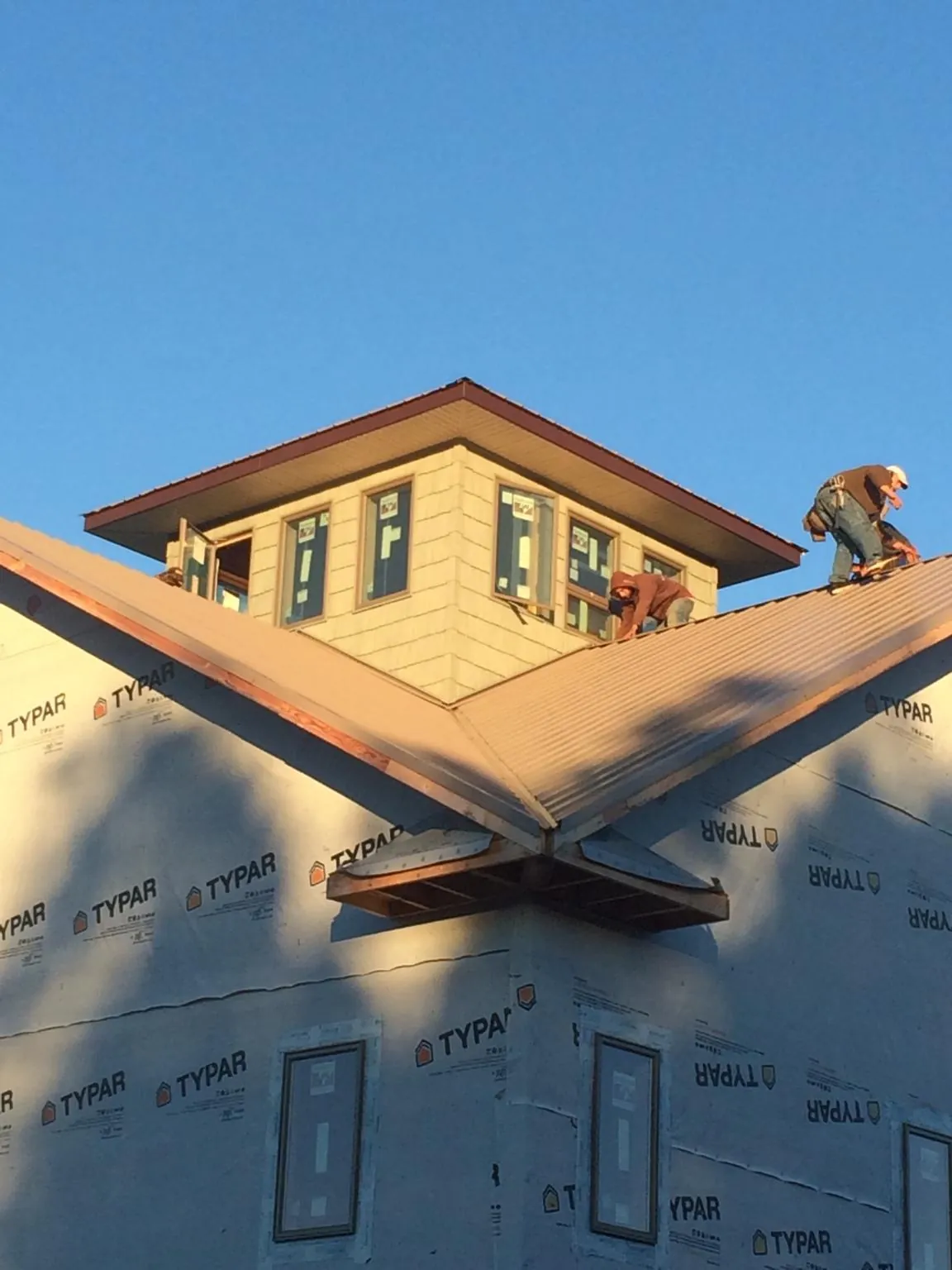 Roofers working around a rooftop cupola on a new metal roof at sunset — Roof Waterproofing in Chillicothe by Roofing Brothers